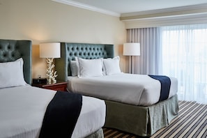 A hotel room with two beds, each with a tufted headboard, white linens, and a striped rug. - Wild Dunes Resort By Destination Hotels (Isle of Palms)