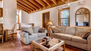 Una sala de estar acogedora con vigas de madera, dos sofás, una mesa de centro y una zona de comedor con sillas.