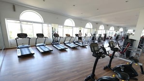 Un gimnasio amplio con numerosas cintas de correr, bicicletas estáticas y máquinas de pesas.