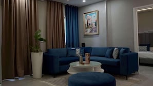Una sala moderna con un sofá azul, una mesa de centro redonda y una planta grande en maceta.