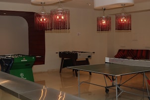 Ein Raum mit einer Fußballplatte, einem Tischtennis-Tisch und einem grünen Heineken-Billiardtisch.