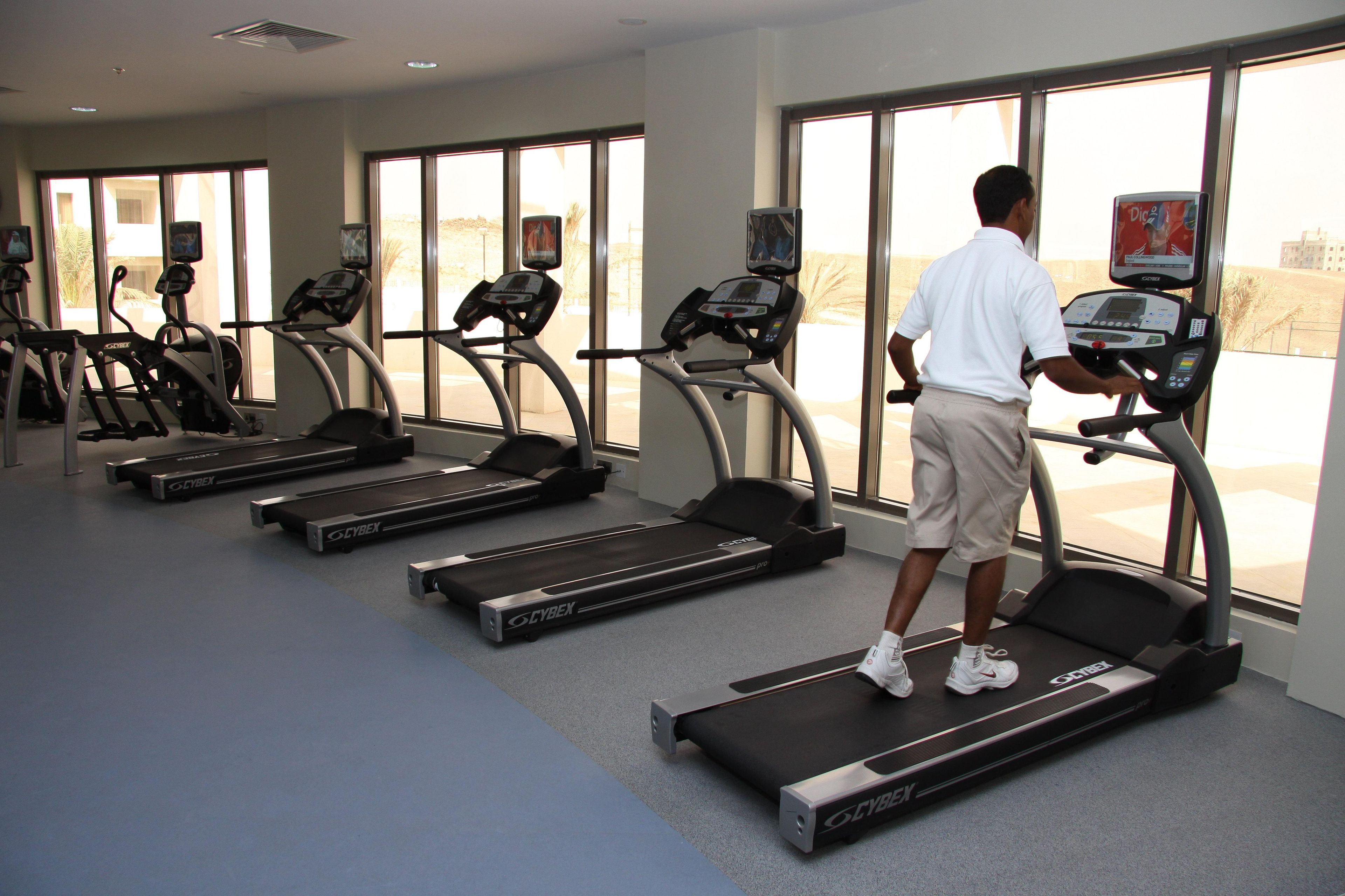 A gym with treadmills, exercise bikes, and a large window.