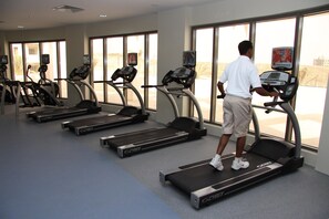 A gym with treadmills, exercise bikes, and a large window. - Crowne Plaza Sohar (Sohar)