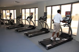 A gym with treadmills, exercise bikes, and a large window.