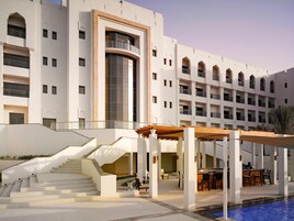A hotel with a pool, outdoor seating, and a staircase leading to the upper floors.