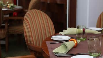 A dining table set with plates, cutlery, and glasses, surrounded by striped chairs.