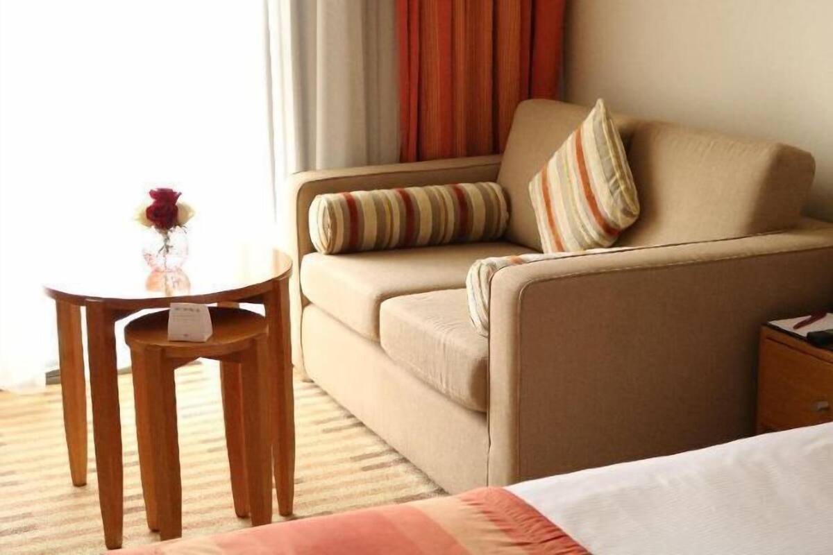 A hotel room with a sofa, a small round table, and a vase with flowers.