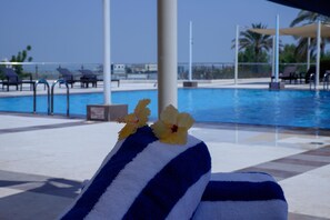 A poolside area with a towel, a flower, and a clear view of the pool. - Crowne Plaza Sohar (Sohar)