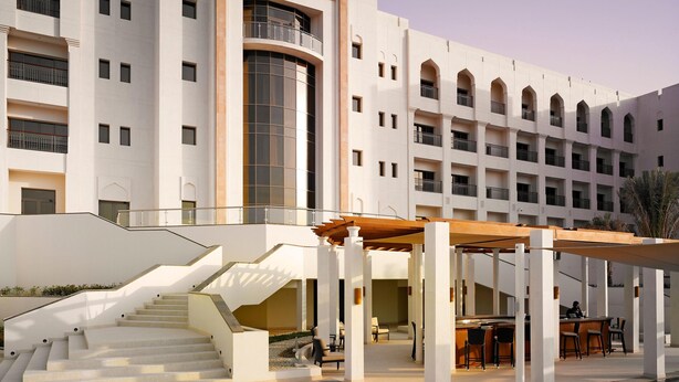 A hotel with a pool, outdoor seating, and a staircase leading to the upper floors. - Crowne Plaza Sohar (Sohar)