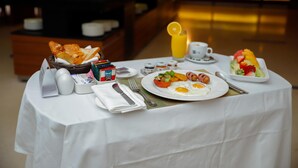 A breakfast table with a basket of bread, a plate of eggs, a glass of orange juice, and a bowl of salad. - Crowne Plaza Sohar (Sohar)