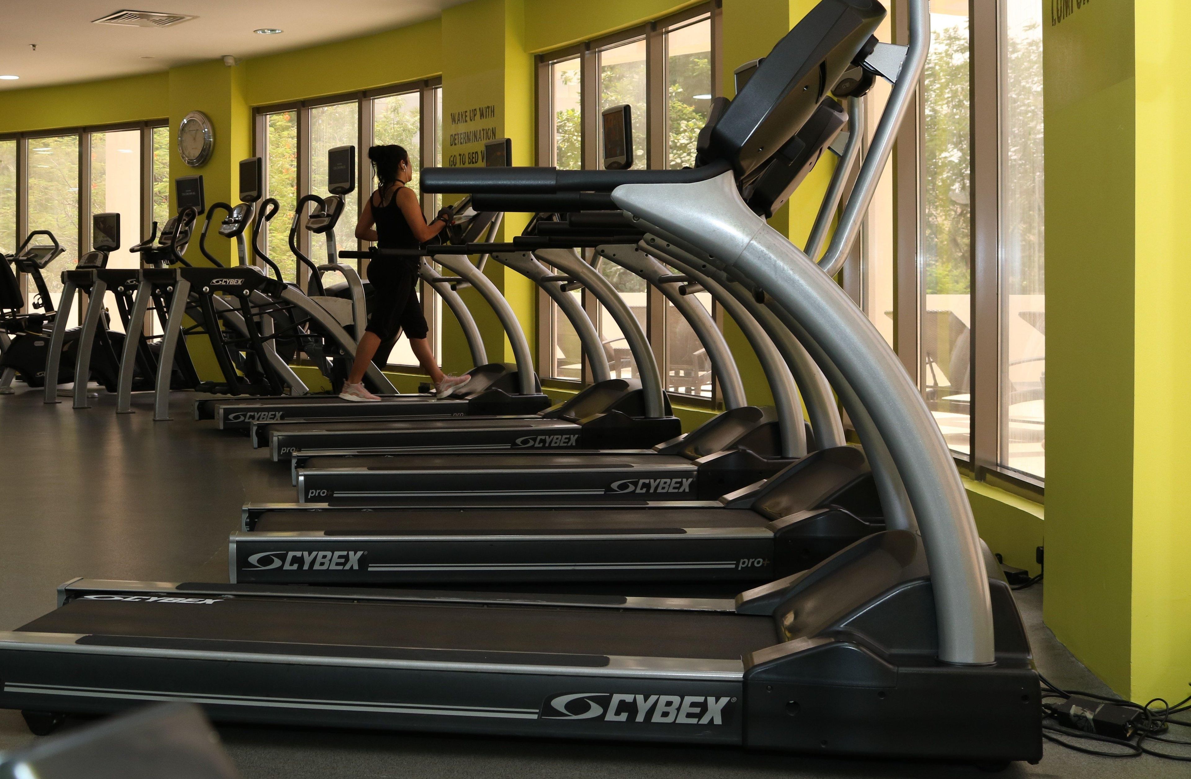 A gym with treadmills, a clock, and a motivational sign on the wall.