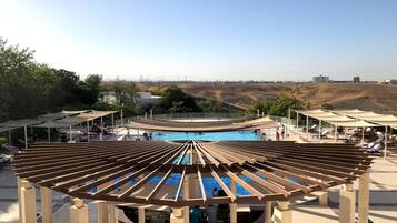 Un área de piscina con un pérgola de madera, sillas de descanso y vistas al paisaje.