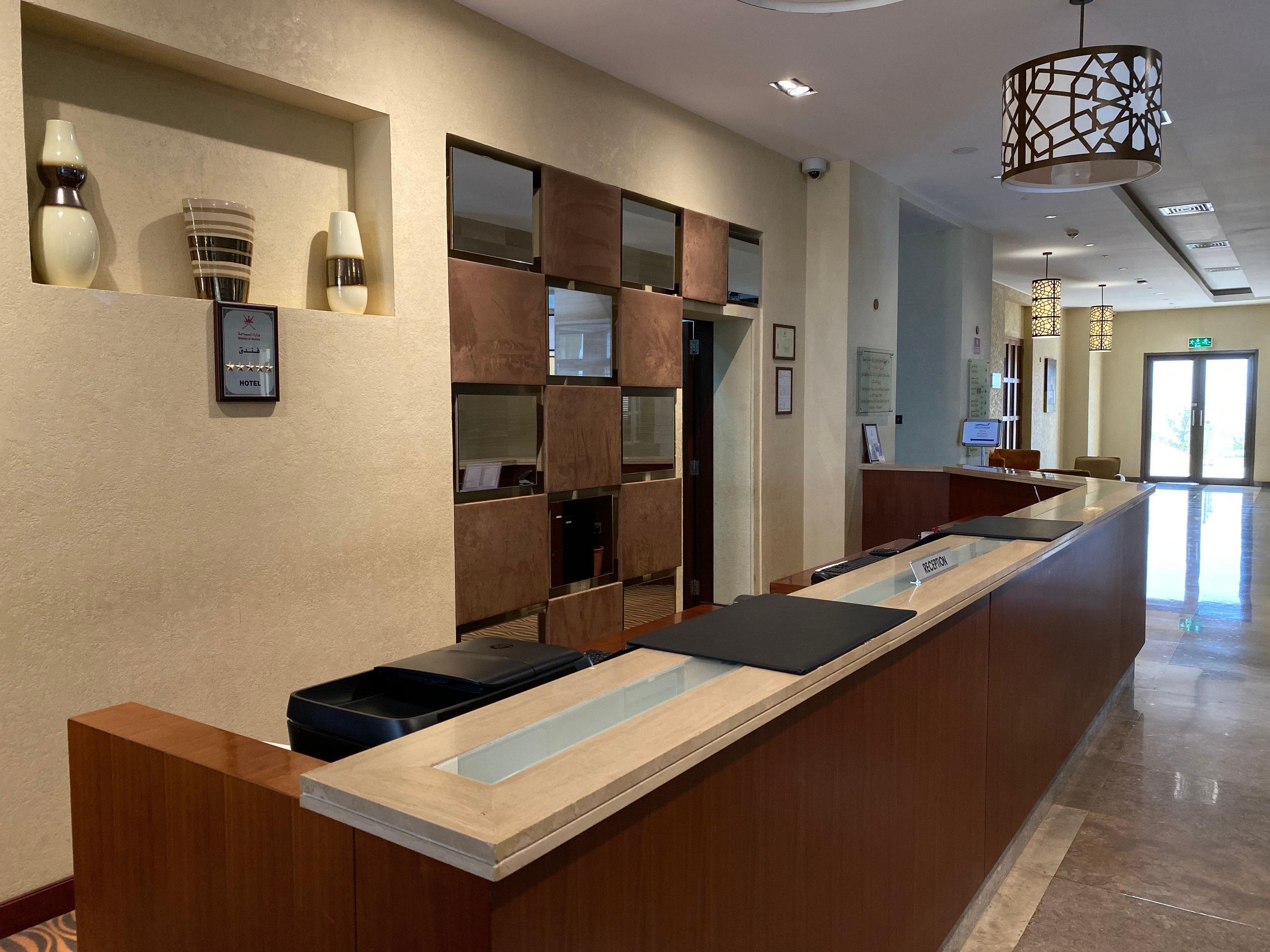 A hotel reception desk with a modern design, a reception area, and a hallway leading to the exit.