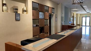 A hotel reception desk with a modern design, a reception area, and a hallway leading to the exit.