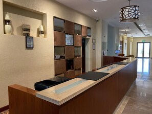 A hotel reception desk with a modern design, a reception area, and a hallway leading to the exit. - Crowne Plaza Sohar (Sohar)