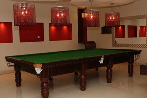 A pool table with a green felt surface, surrounded by red walls and wooden legs. - Crowne Plaza Sohar (Sohar)