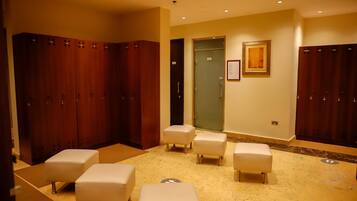 A hotel room with a marble floor, wooden lockers, and white cushioned seating areas.
