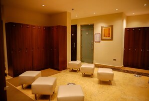 A hotel room with a marble floor, wooden lockers, and white cushioned seating areas. - Crowne Plaza Sohar (Sohar)