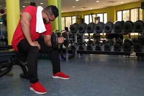 A gym with exercise equipment, a bench, and a person lifting weights. - Crowne Plaza Sohar (Sohar)