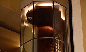 A corner room with a glass partition, a ceiling-mounted security camera, and a wooden cabinet. - Crowne Plaza Sohar (Sohar)