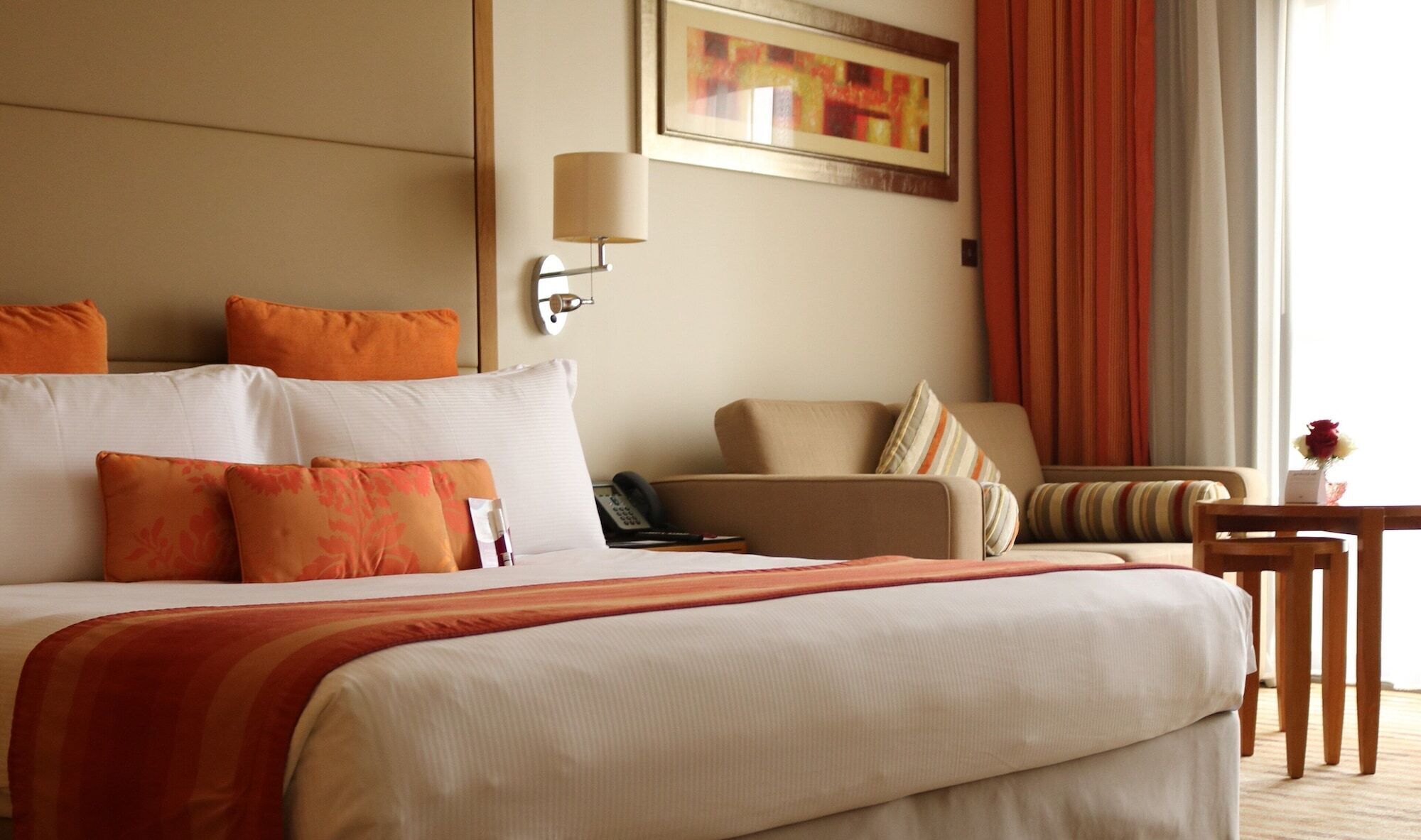 Una habitación de hotel con una cama grande, una silla, una mesita y un cuadro en la pared.