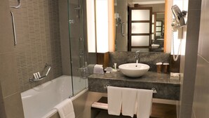Un baño moderno con cabina de ducha de vidrio, una bañera blanca y un lavamanos amplio.