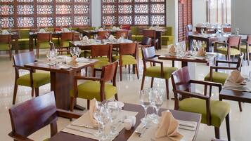 A restaurant with multiple tables and chairs, each set with glassware and napkins.