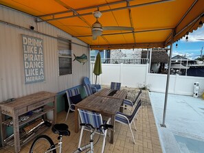 An outdoor patio with wooden tables and chairs, a bicycle, and a sign that reads "DRINK LIKE A PIRATE DANCE LIKE A MERMAID". - Family Fishing Shack Tavernier Key (Tavernier)