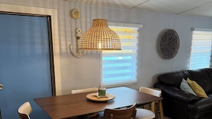 A dining area with a wooden table and chairs, a hanging lamp, and a blue door.