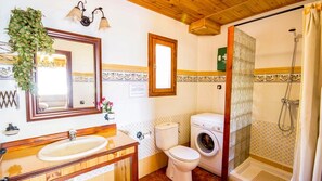 Une salle de bain avec un meuble-lavabo en bois, un évier, des toilettes, un lave-linge et une douche.