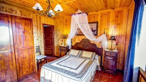 A wooden-paneled bedroom with a four-poster bed, a nightstand, a chair, and a chandelier. - Las Olivas Sayalonga by Ruralidays (Málaga)