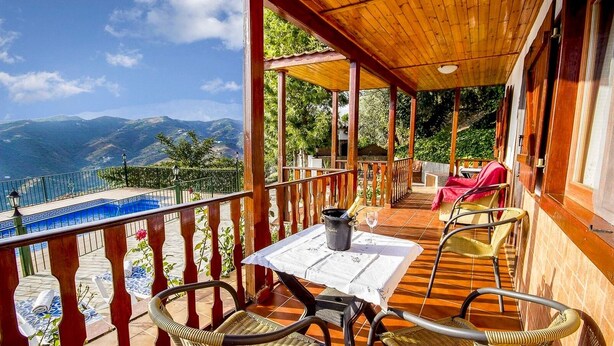 A covered outdoor seating area with a table, chairs, and a view of mountains. - Las Olivas Sayalonga by Ruralidays (Málaga)