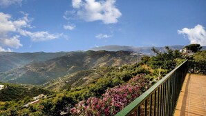 A scenic view of a mountainous landscape with a wooden walkway and flowering plants. - Las Olivas Sayalonga by Ruralidays (Málaga)