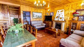 A wooden interior with a dining table, sofa, fireplace, and television. - Las Olivas Sayalonga by Ruralidays (Málaga)