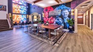 Una sala conferenze con un tavolo grande, sedie e un murale raffigurante combattenti di 'The Ultimate Fighter'.