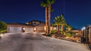 Una strada privata con garage, palme e un vialetto ben illuminato.