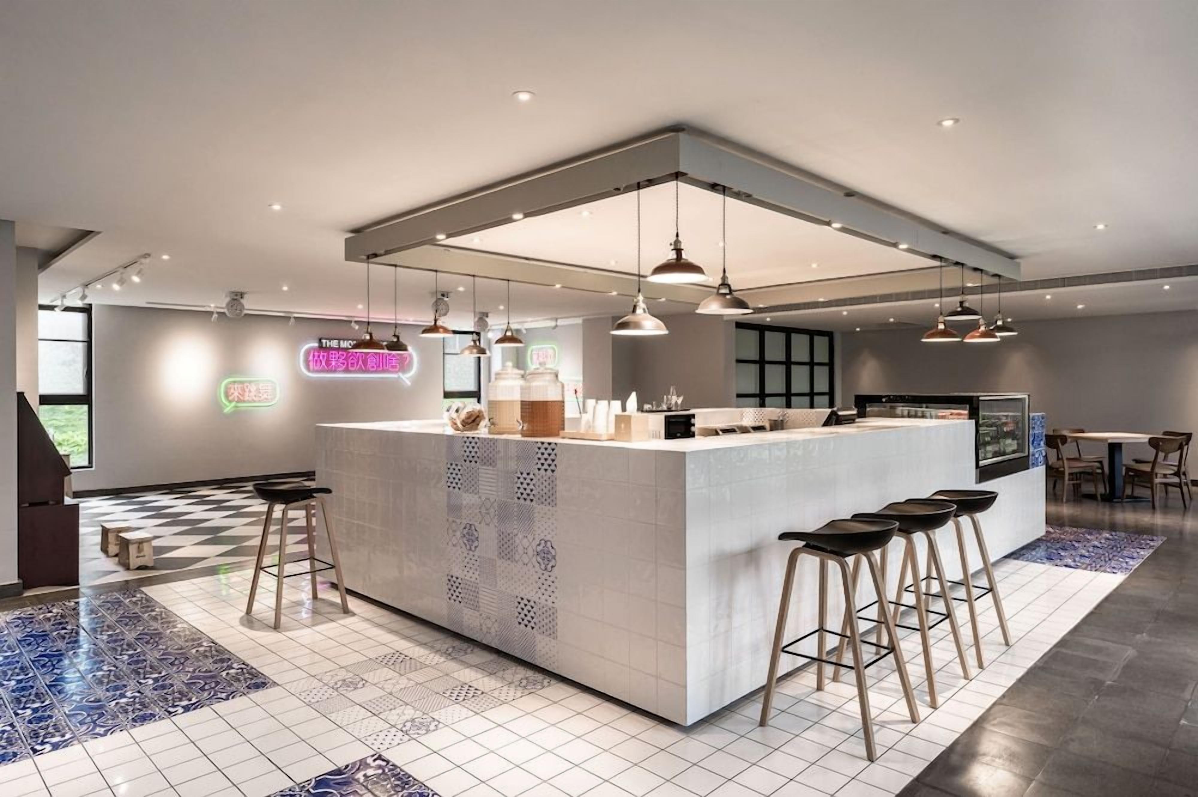 A modern kitchen with a central island, bar stools, pendant lighting, and a checkered floor pattern.
