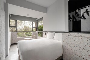A modern bedroom with a large bed, a small table, and a view of greenery through large windows. - The Moment Hotel Yilan by Lakeshore (Wujie)