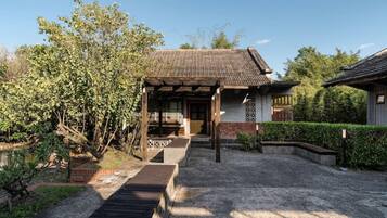 A traditional Japanese-style house with a wooden porch, a gravel pathway, and a garden with various plants.