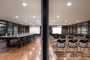 A conference room with a long table, chairs, a projector screen, and a whiteboard. - The Moment Hotel Yilan by Lakeshore (Wujie)