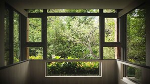 A room with large windows offering a view of dense greenery outside. - The Moment Hotel Yilan by Lakeshore (Wujie)