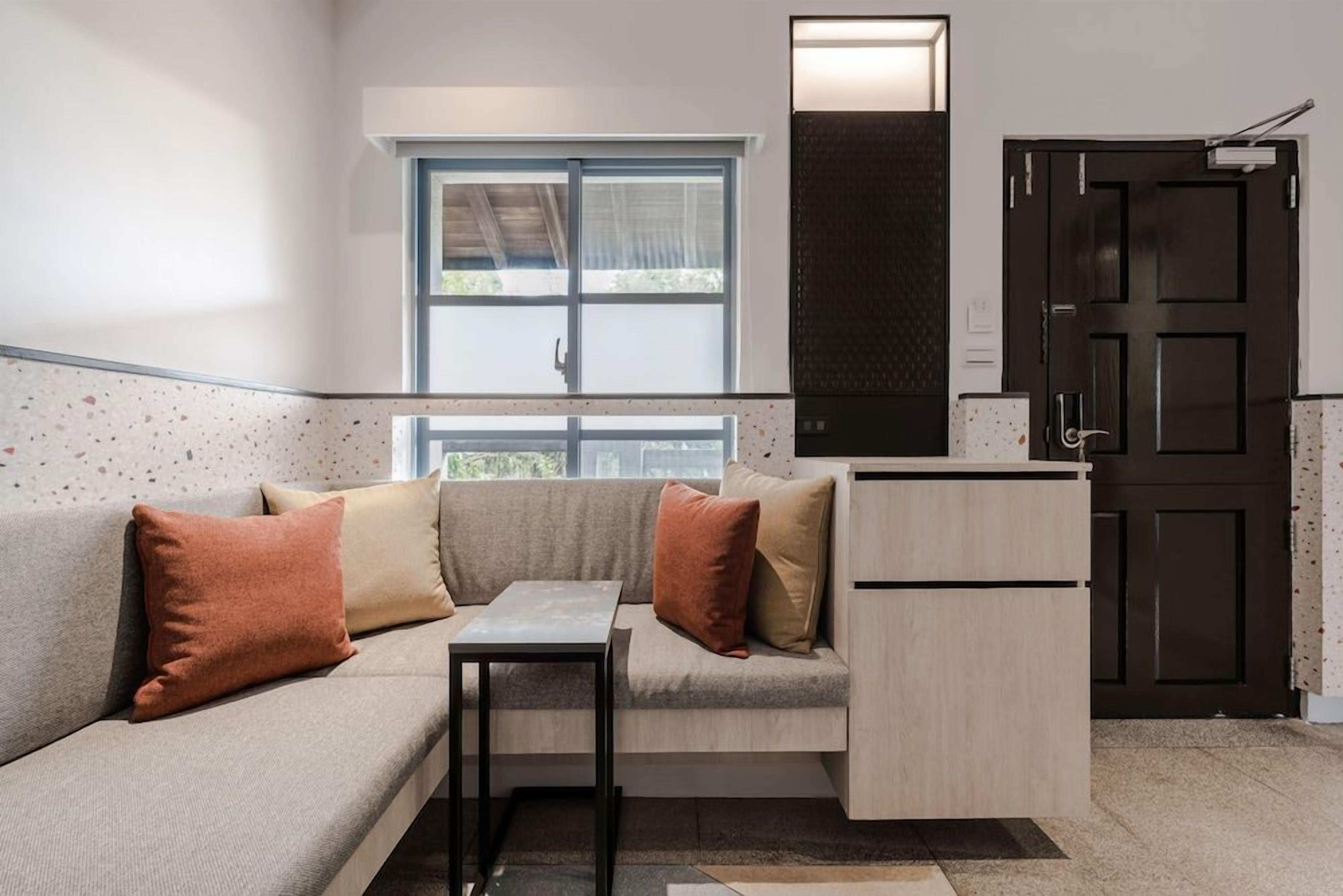 A compact living space with a sofa, a small table, a cabinet, and a door.