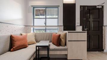 A compact living space with a sofa, a small table, a cabinet, and a door.