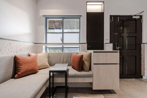 A compact living space with a sofa, a small table, a cabinet, and a door. - The Moment Hotel Yilan by Lakeshore (Wujie)
