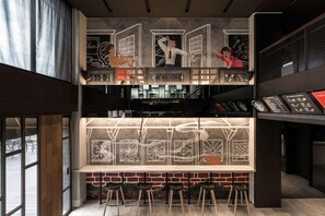 A bar area with a counter, stools, and a mural. - The Moment Hotel Yilan by Lakeshore (Wujie)