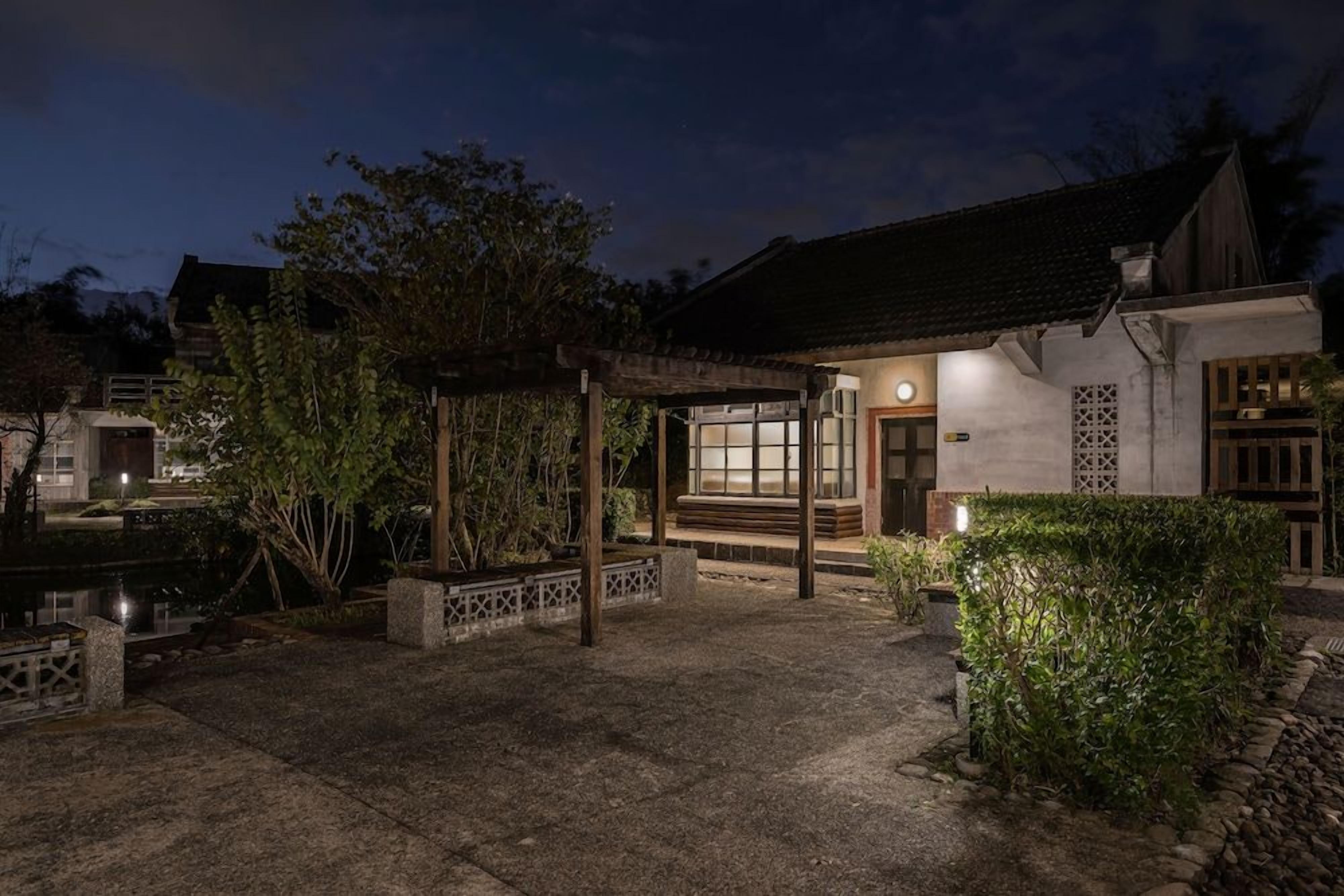 A traditional building with a covered entrance, a stone pathway, and a small garden area.