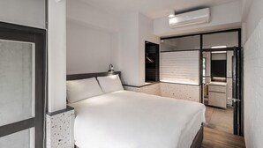 Una habitación de hotel moderna con una cama grande, un armario empotrado y una puerta corredera que da acceso a un baño.
