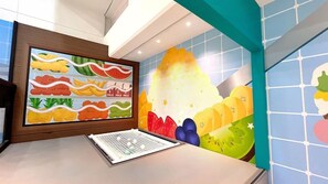 A reception area with a colorful fruit-themed wall mural and a reception desk. - The Moment Hotel Yilan by Lakeshore (Wujie)
