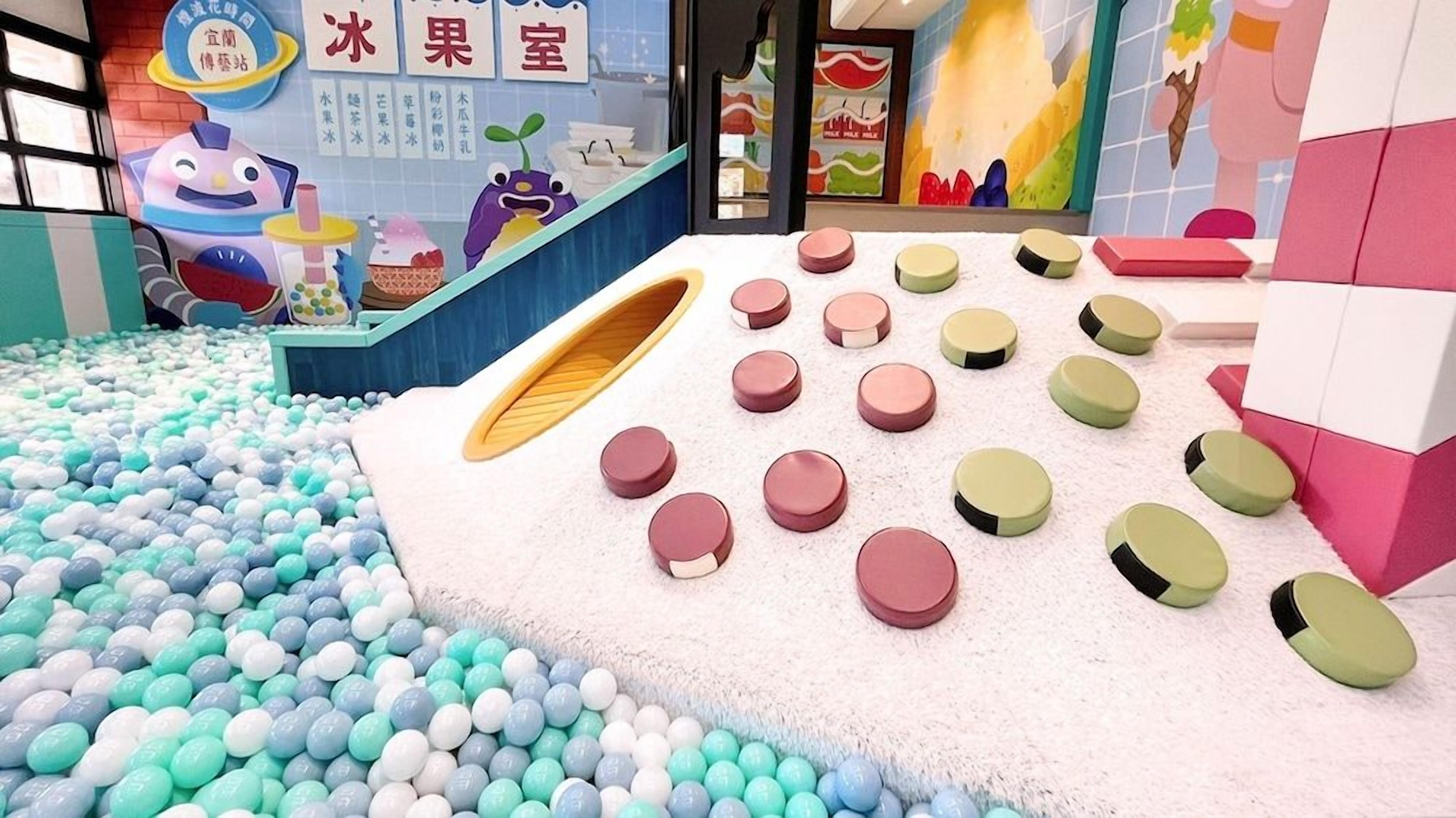 A children's play area with a ball pit, colorful stools, and a cartoon character.