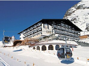 A multi-story building with a ski lift in the foreground. - Almhof Hotel (Galtur)